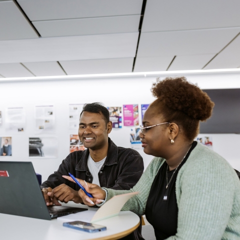Two students looking at a laptop
