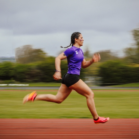 Athletics club member running along the track