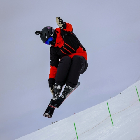 Student skiier in mid air over a jump
