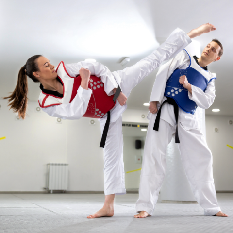 Woman and man practising kicking in taekwondo