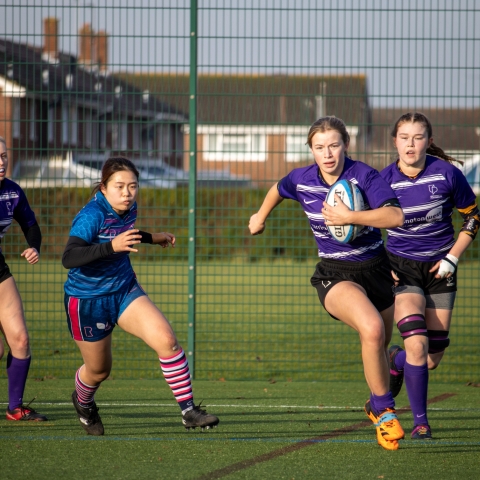 women's rugby player running with the ball