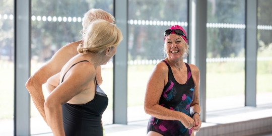 Three people smiling and talking at pool edge - Ravelin Activities