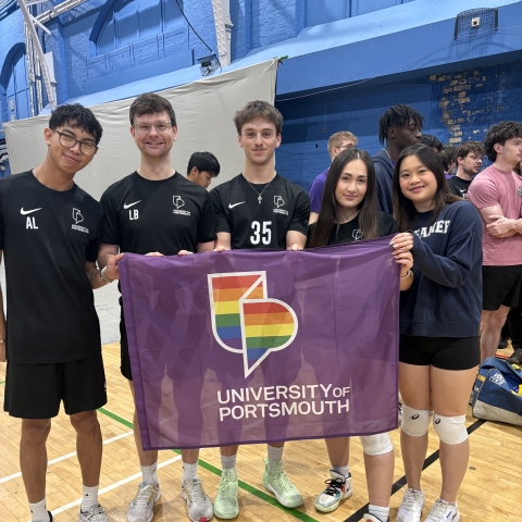 Team UOP students posing with a UOP pride flag