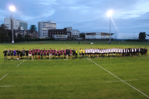Football players standing in line, side-by-side, on the pitch during dusk