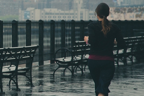 Woman running along sea front in the rain