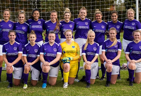 Women's football team kneeling for photograph in their purple UoP kit before their match