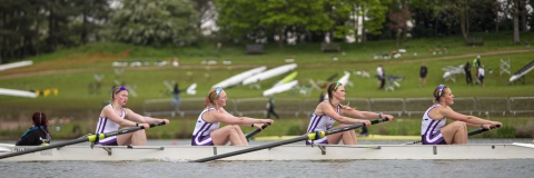 four students rowing on a lake