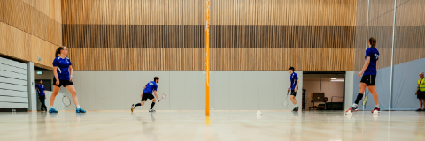 Student playing badminton in sports hall