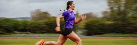 Athletics club member running along the track