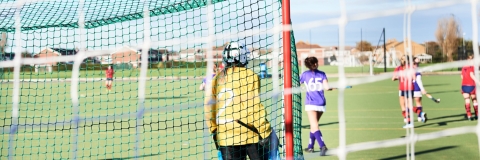 Women playing hockey on a grass pitch