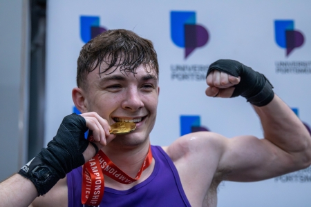 Louis Silk biting Gold medal, won during the BUCS National Championships 2025