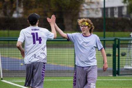 student high fiving whilst playing ultimate frisbee