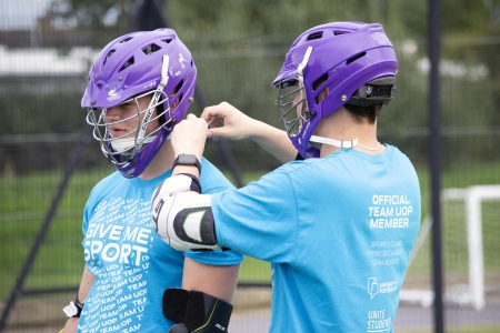Two lacrosse players preparing their helmets before a game