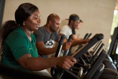 Four gym users on elliptical machines